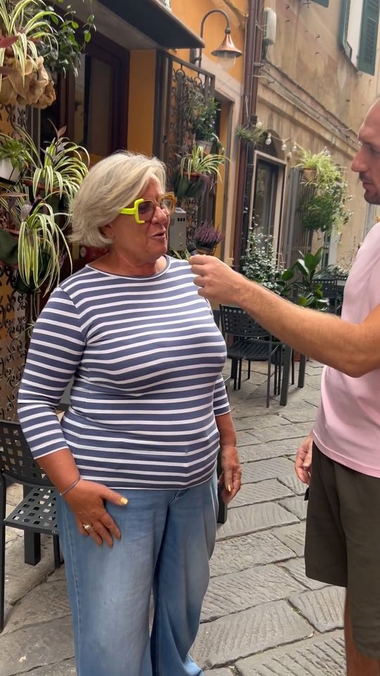 Stefano col microfono fa una domanda a una signora per le vie di Finalborgo